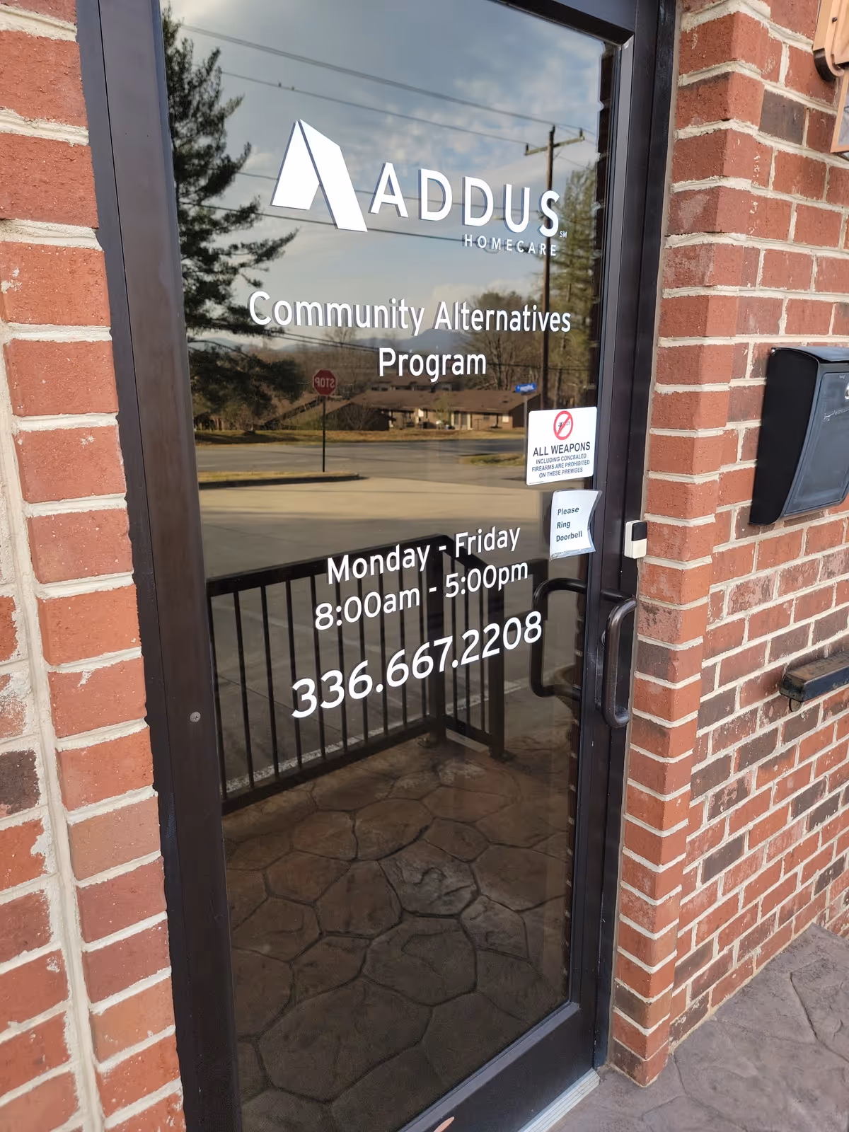 Glass door entrance at Addus HomeCare displaying Community Alternatives Program signage.