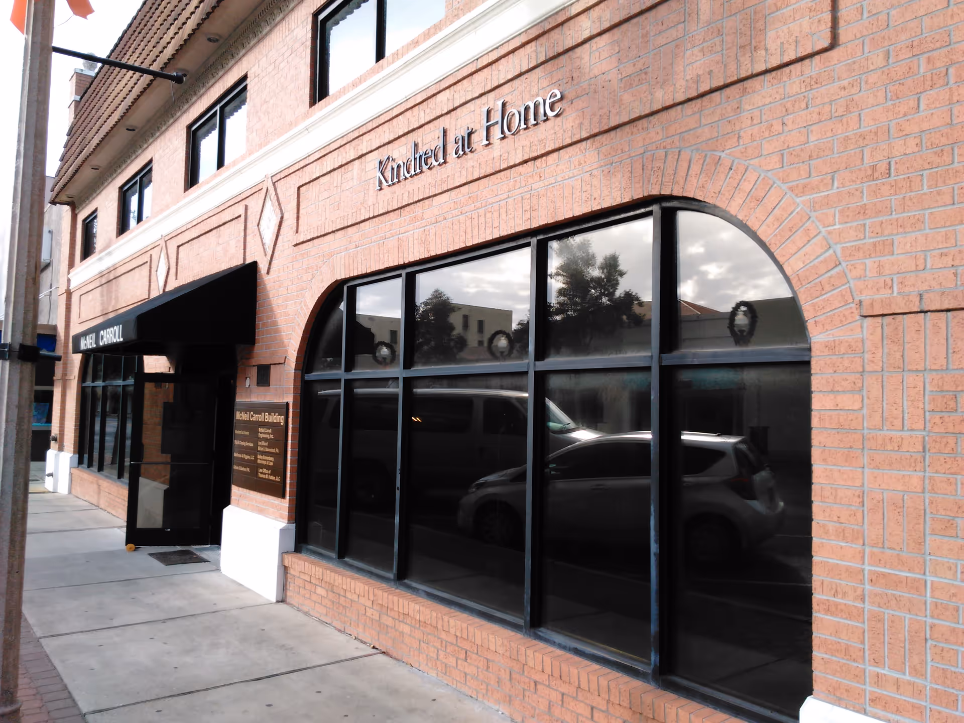 Brick building exterior with large arched windows and Kindred at Home signage.