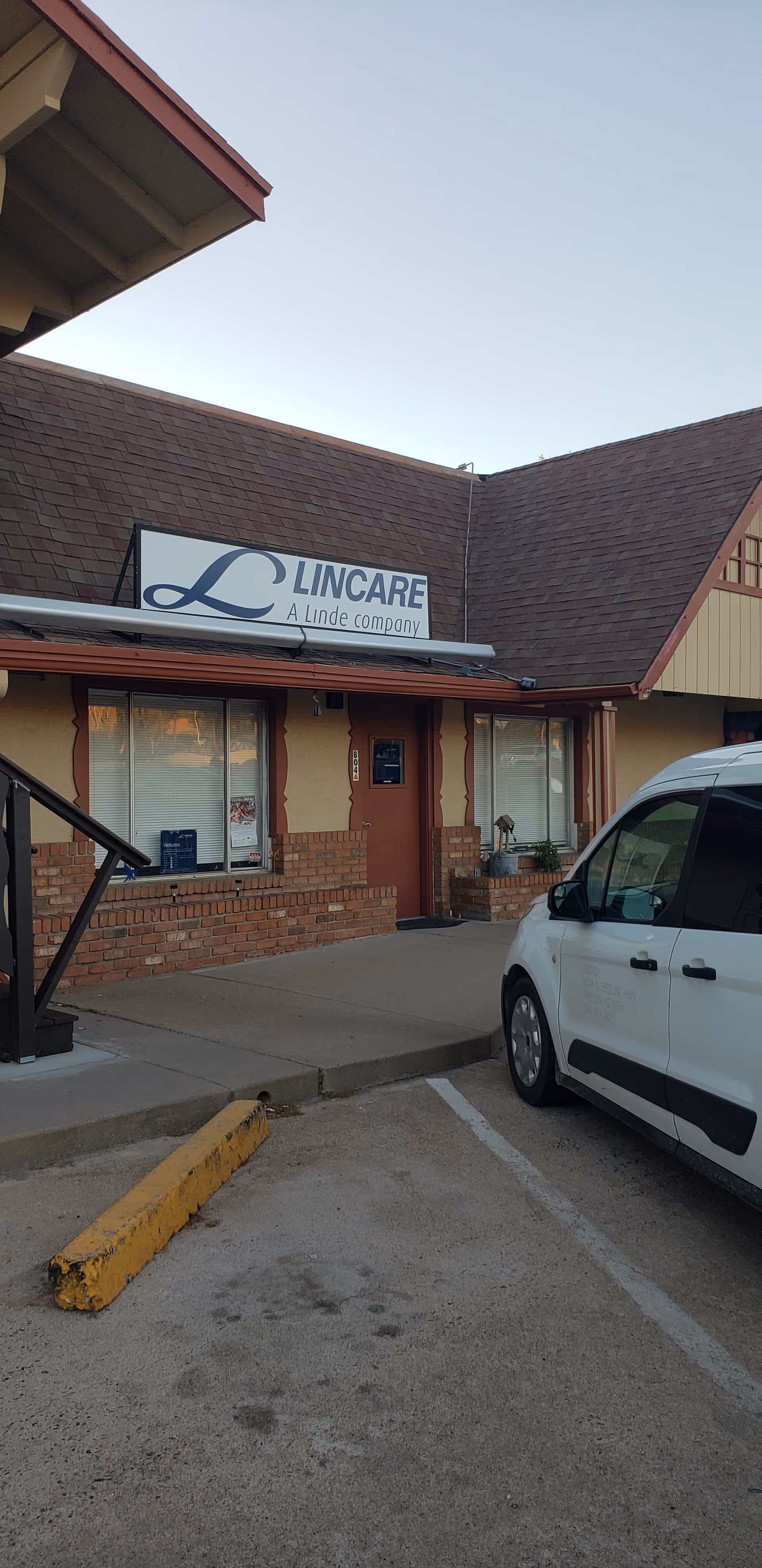 Exterior view of a LINCARE facility with a sign and a parked white van.