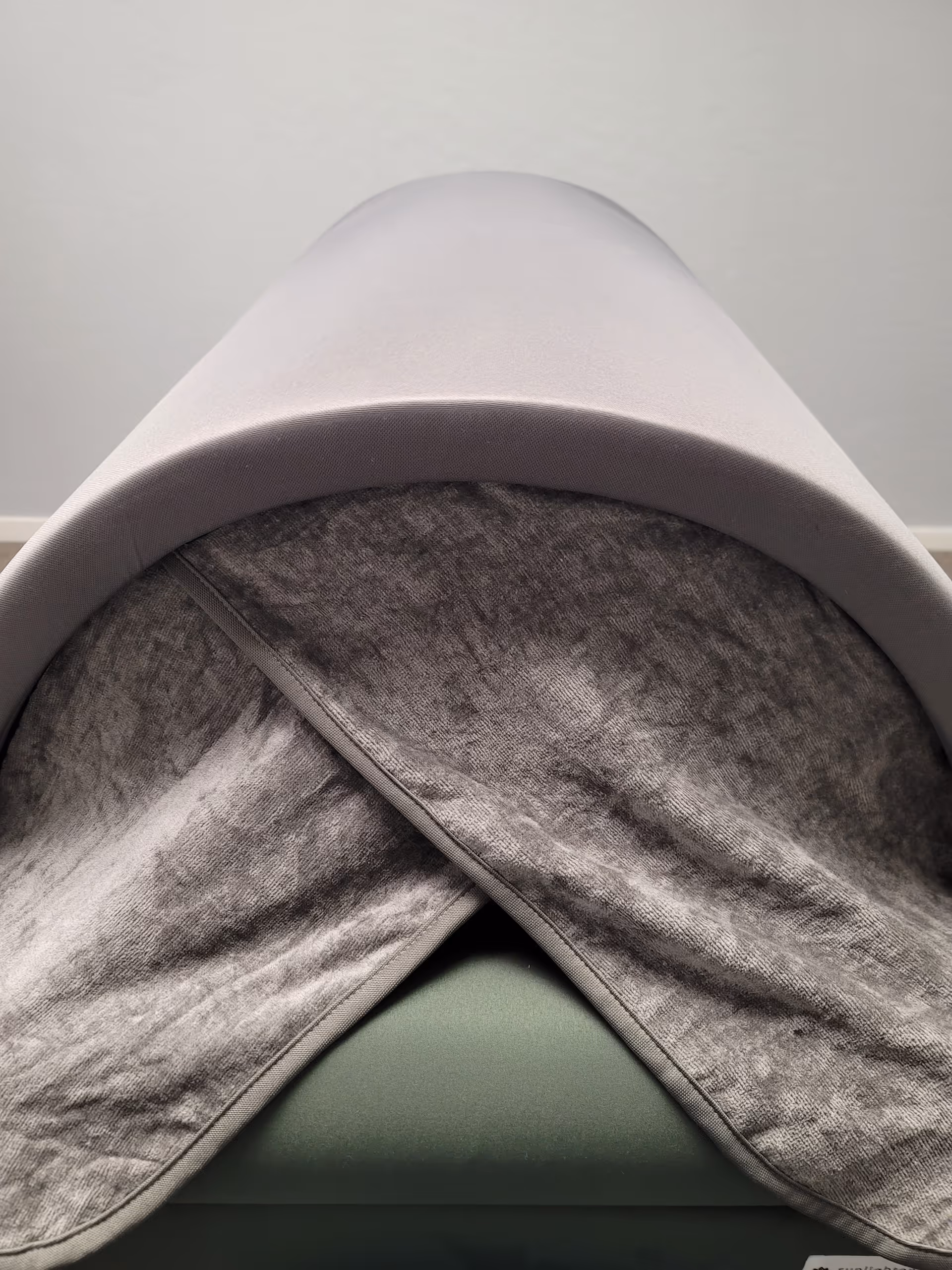 Close-up of a curved massage table headrest with a folded gray blanket.
