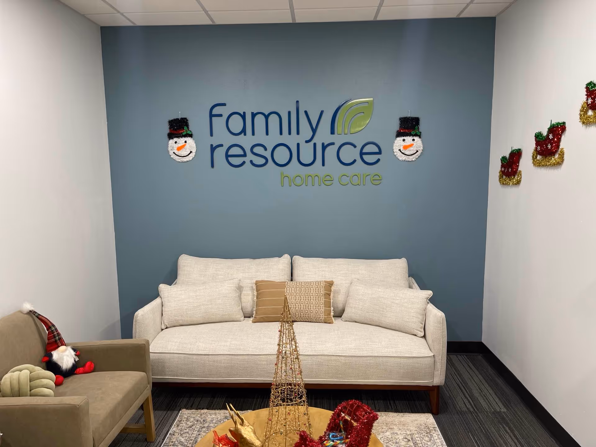 Lounge area with light sofa, holiday decorations, and a wall sign reading Family Resource Home Care.