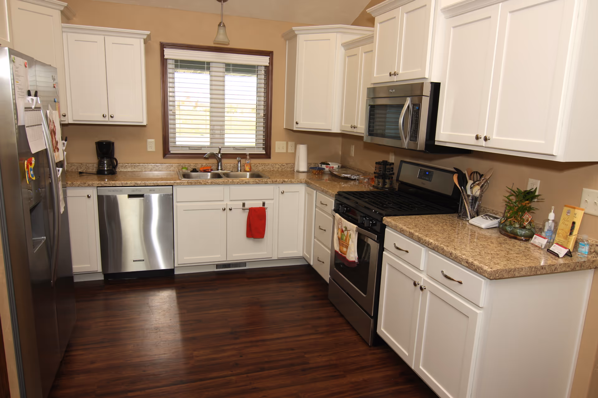 Bright kitchen with white cabinets, stainless steel appliances, granite countertops, and a window above the sink.