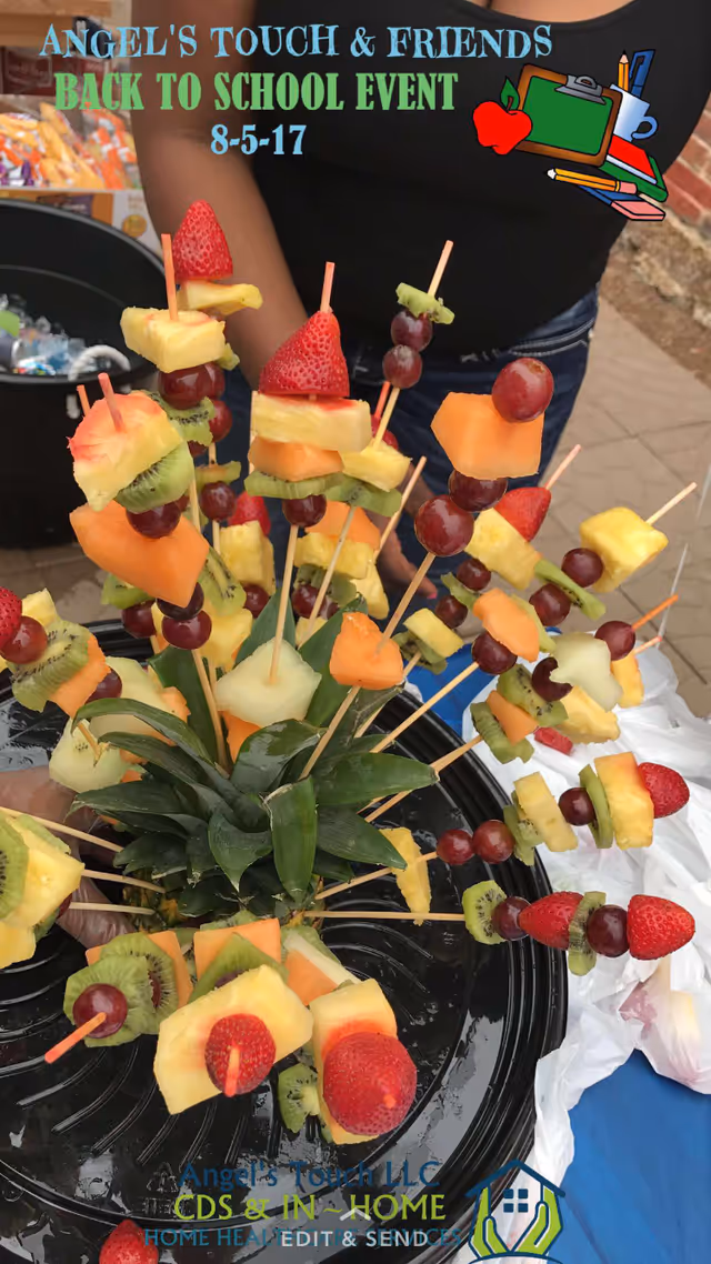 Outdoor display of colorful fruit skewers on a platter with a person behind