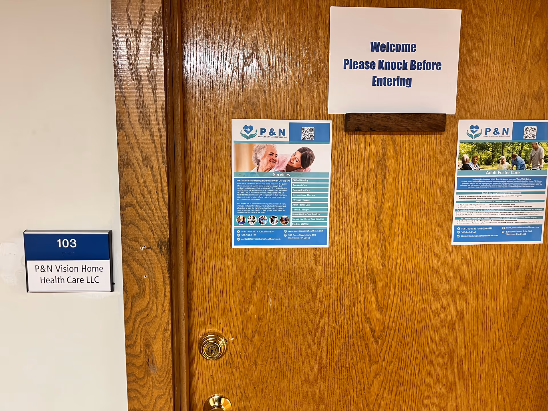 Wooden interior door with welcome sign and P&N Vision posters in a hallway.