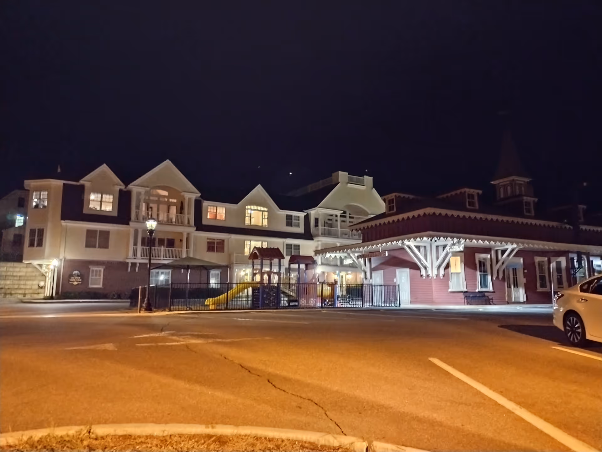 Night exterior of Home Instead senior facility with a playground and parked car.
