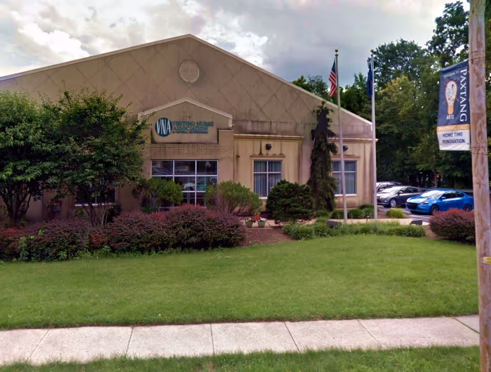 Exterior view of Visiting Nurse Association building with lawn and flagpoles