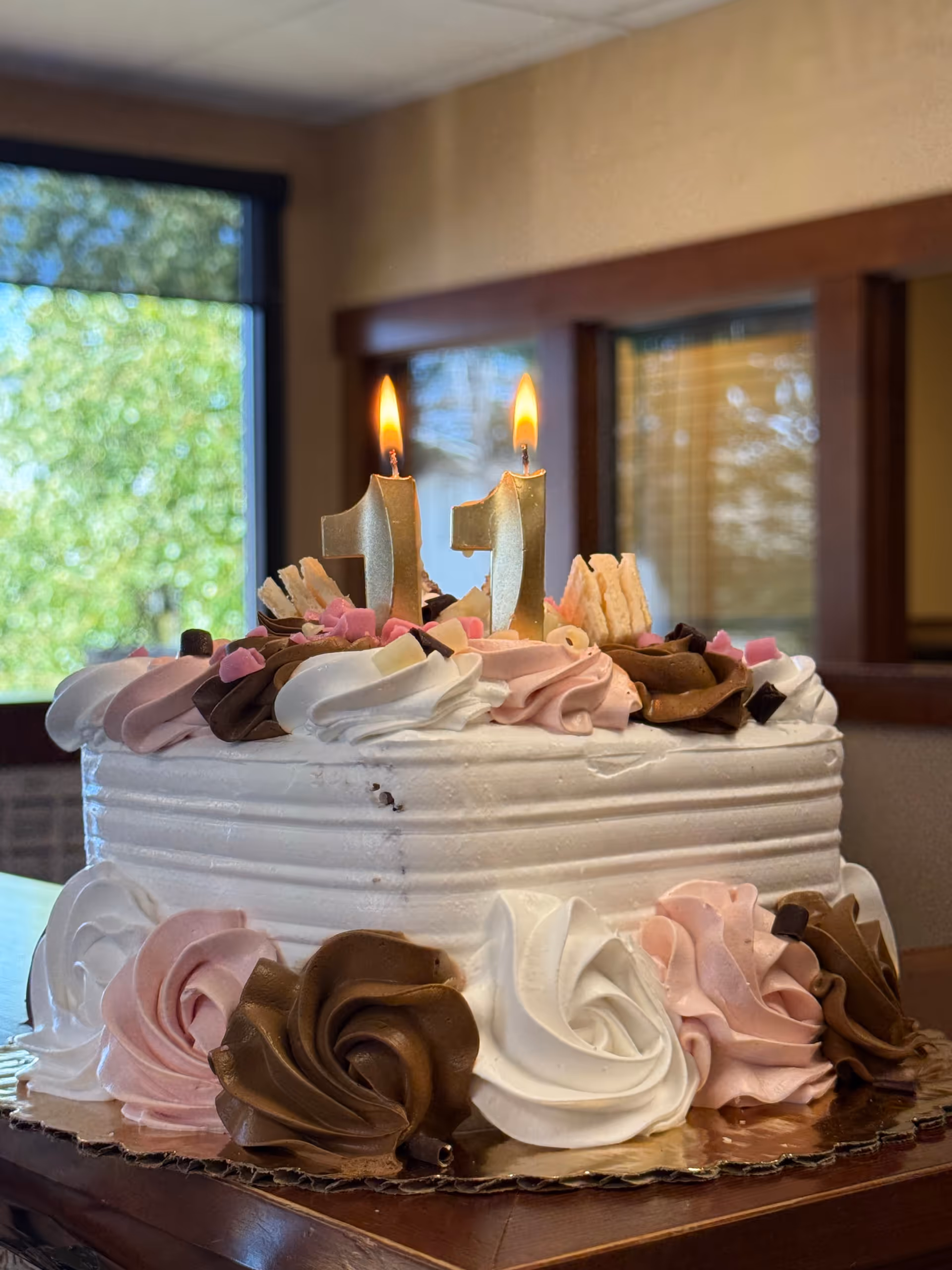 Decorated birthday cake with lit candles sits on a table indoors.