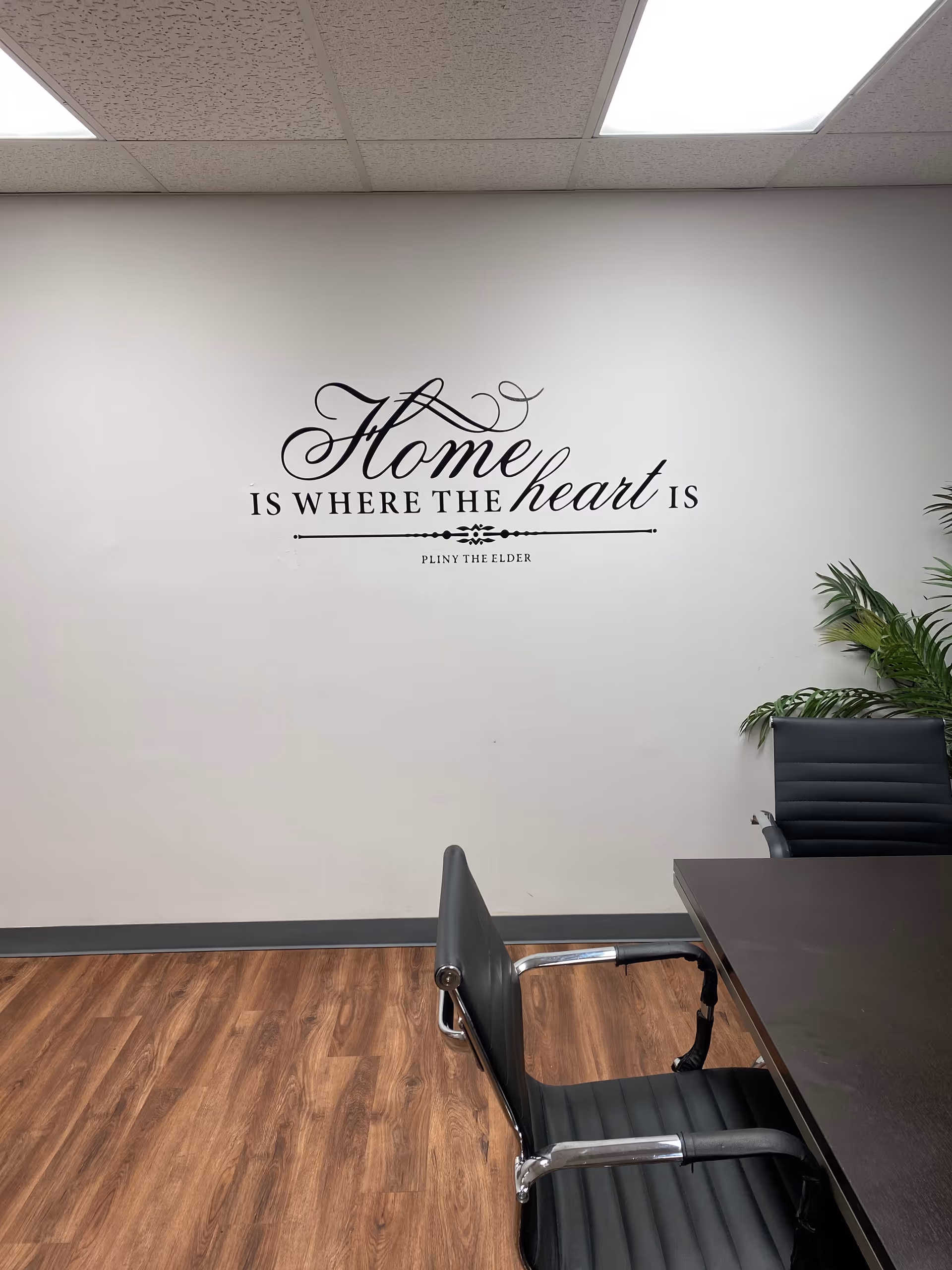 Interior office space with wall art 'Home is where the heart is' and a table.
