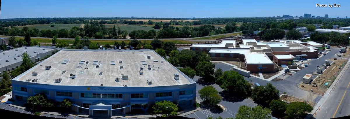 Aerial view of a multi-building senior living campus with parking and trees.