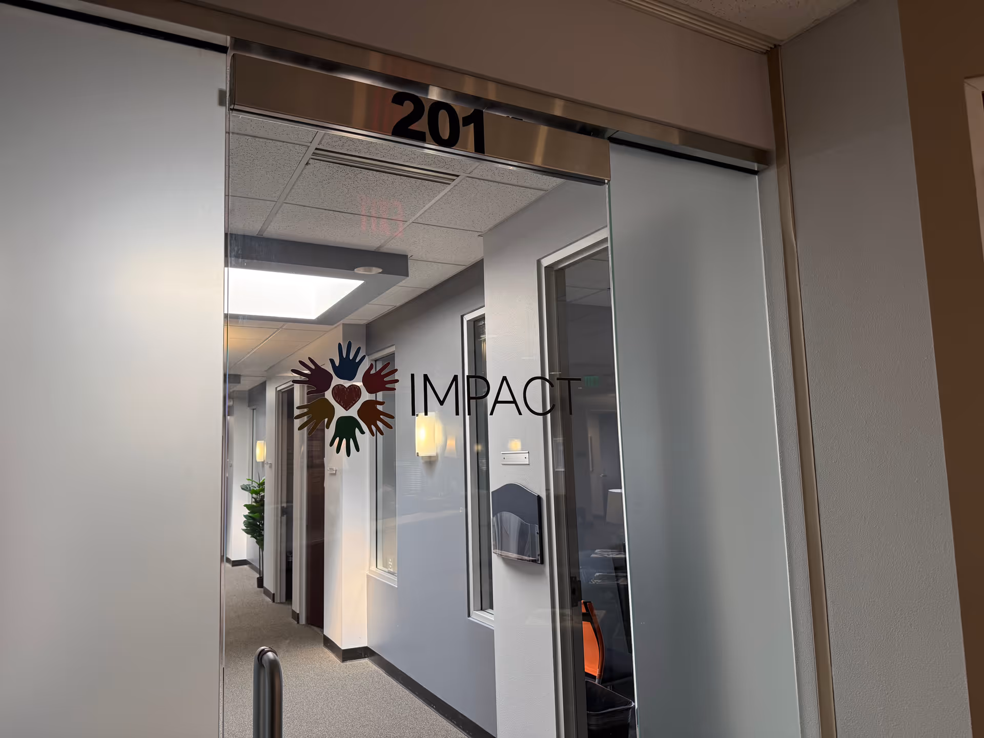 Interior glass doorway with IMPACT logo and hallway, room 201 visible.