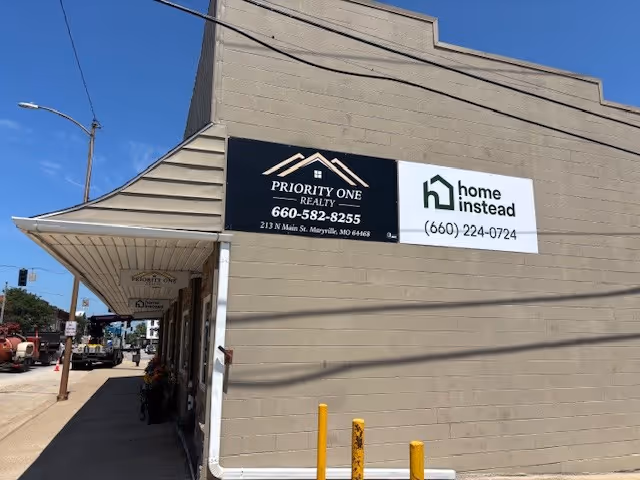 Exterior view of a building with Priority One Realty and Home Instead signs.