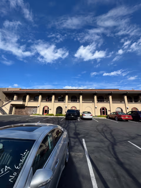 A beige two-story senior living facility with arches and a front parking lot.