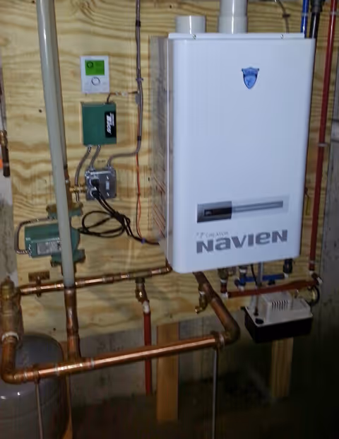 Basement utility room with Navien tankless water heater and copper piping.