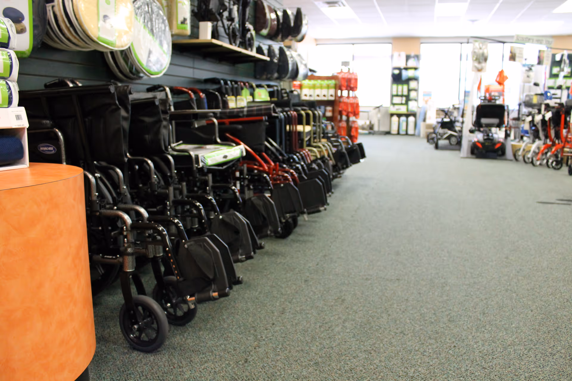 A showroom aisle filled with wheelchairs, walkers, and mobility equipment on shelves.