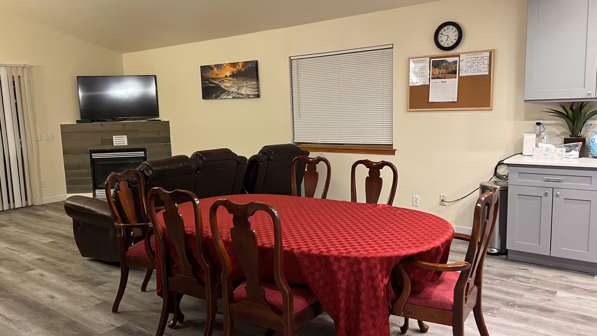 Common living area featuring a red tablecloth dining table, chairs, sofa, and kitchenette.
