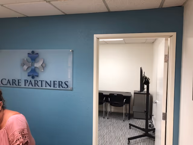 Blue hallway wall with Care Partners sign and doorway to a small meeting room.
