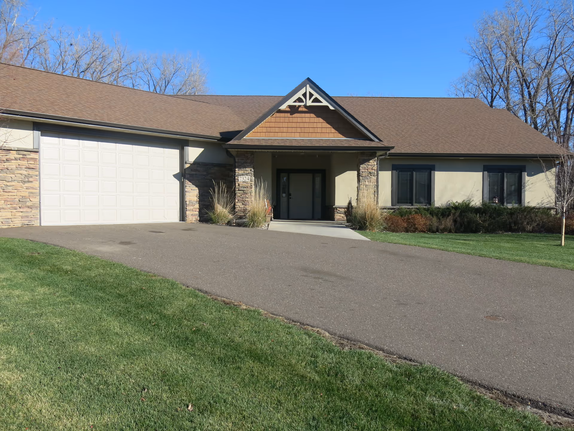 Single-story building with stone accents and a wide driveway leading to a front entrance.