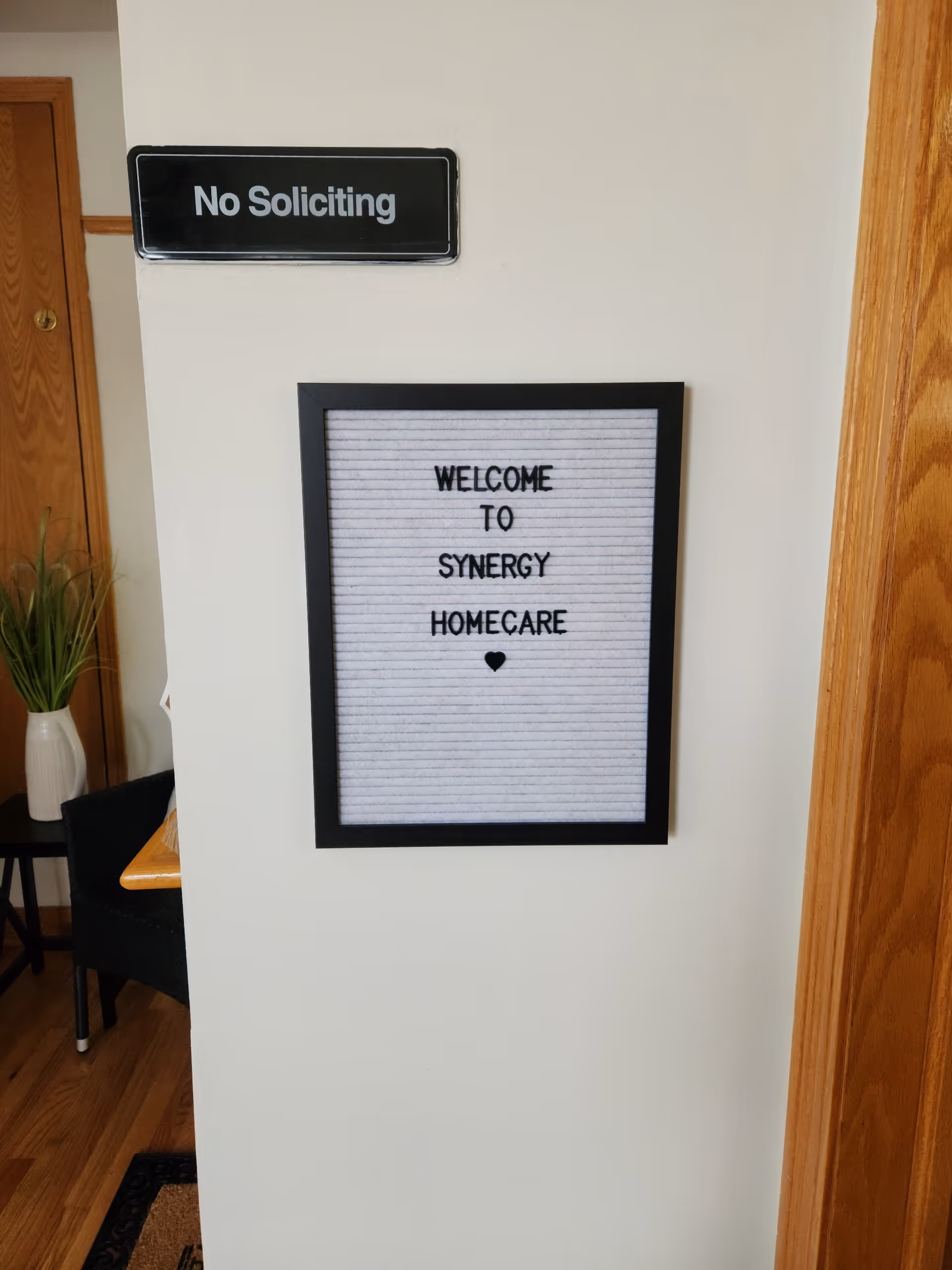 Hallway wall featuring a No Soliciting sign and a framed Welcome to Synergy HomeCare board