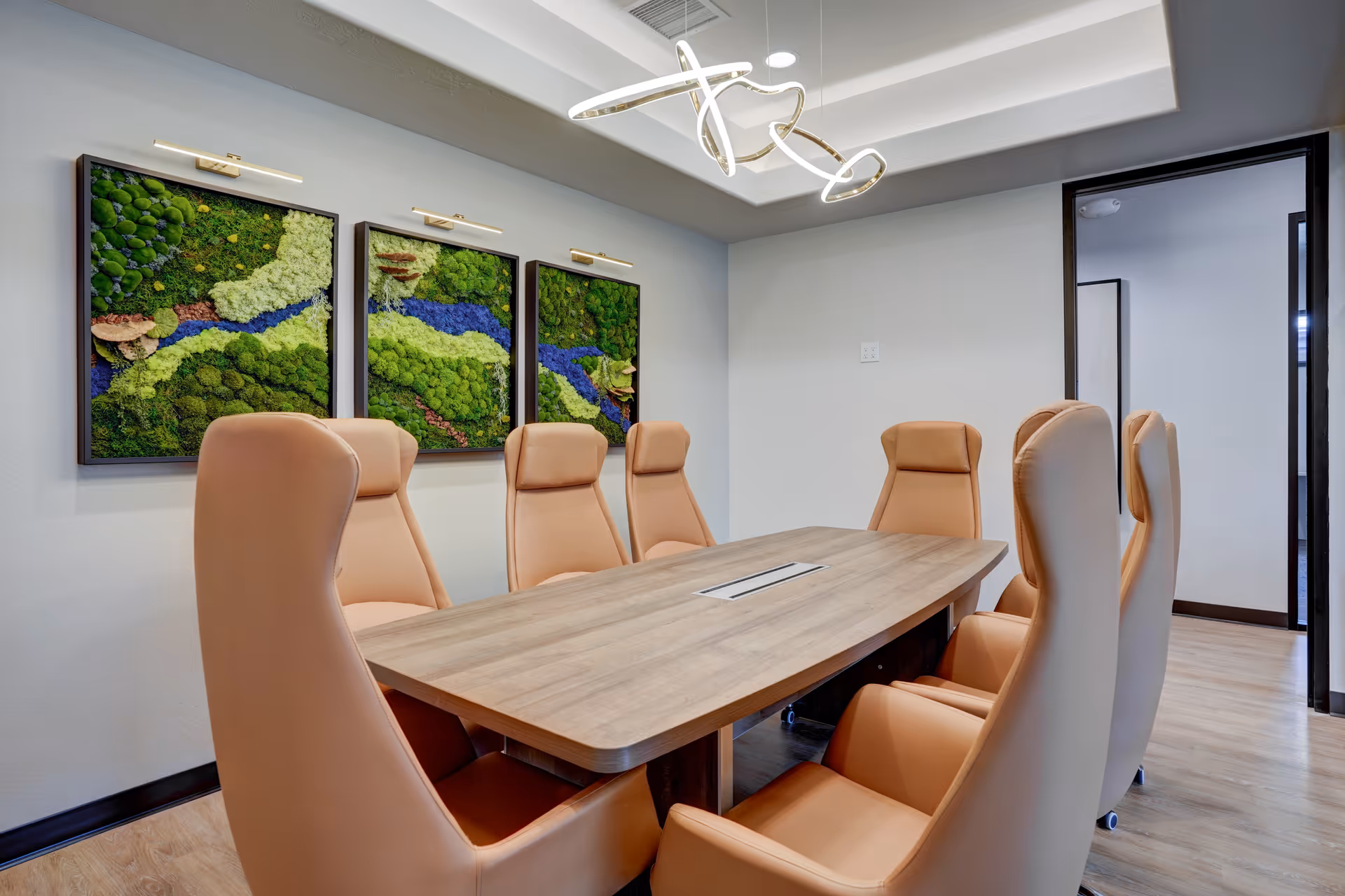 A modern conference-style meeting room with a long wooden table and beige high-backed chairs.
