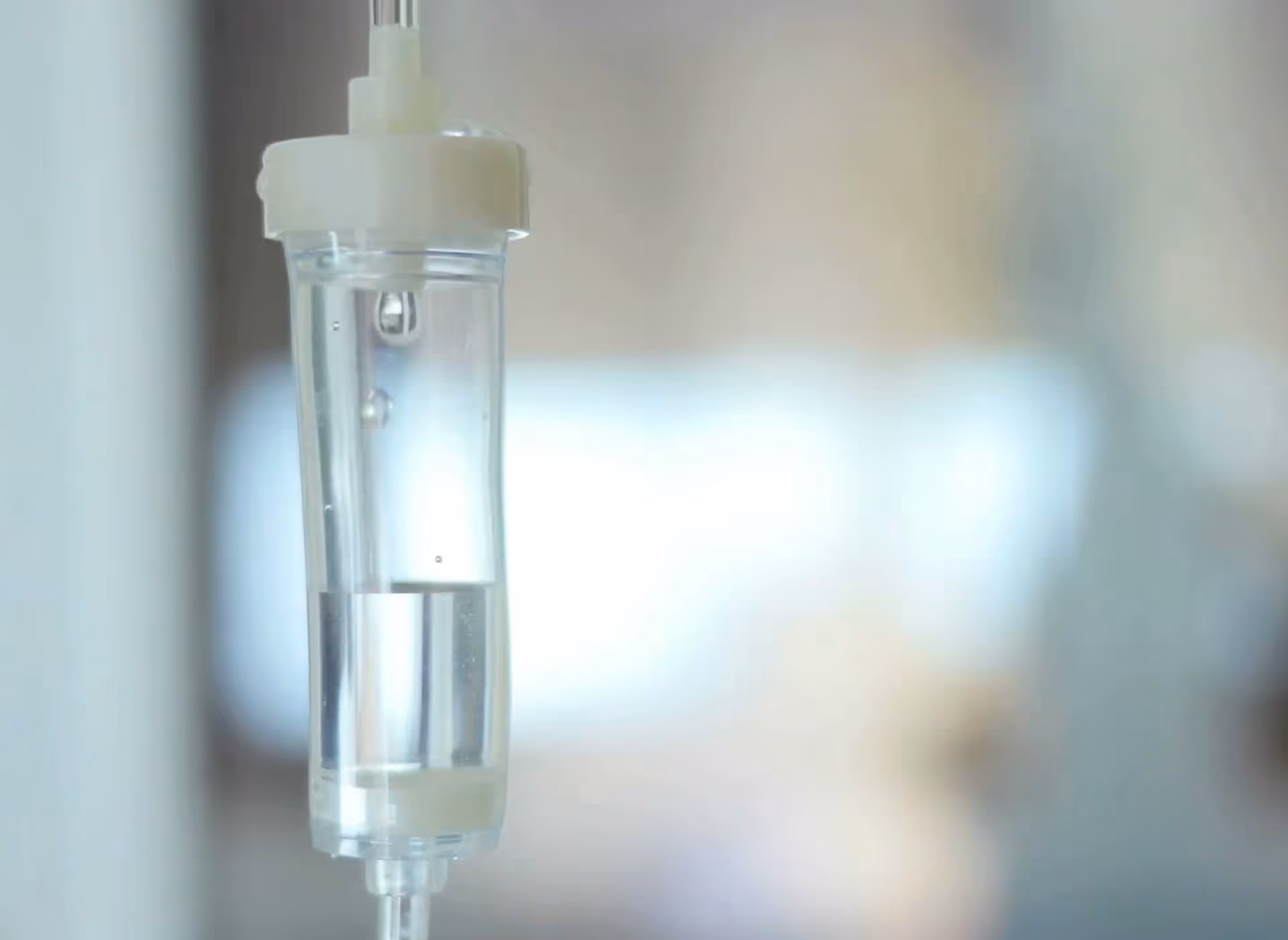 Close-up of an IV drip bag attached to a medical stand in a clinical setting.