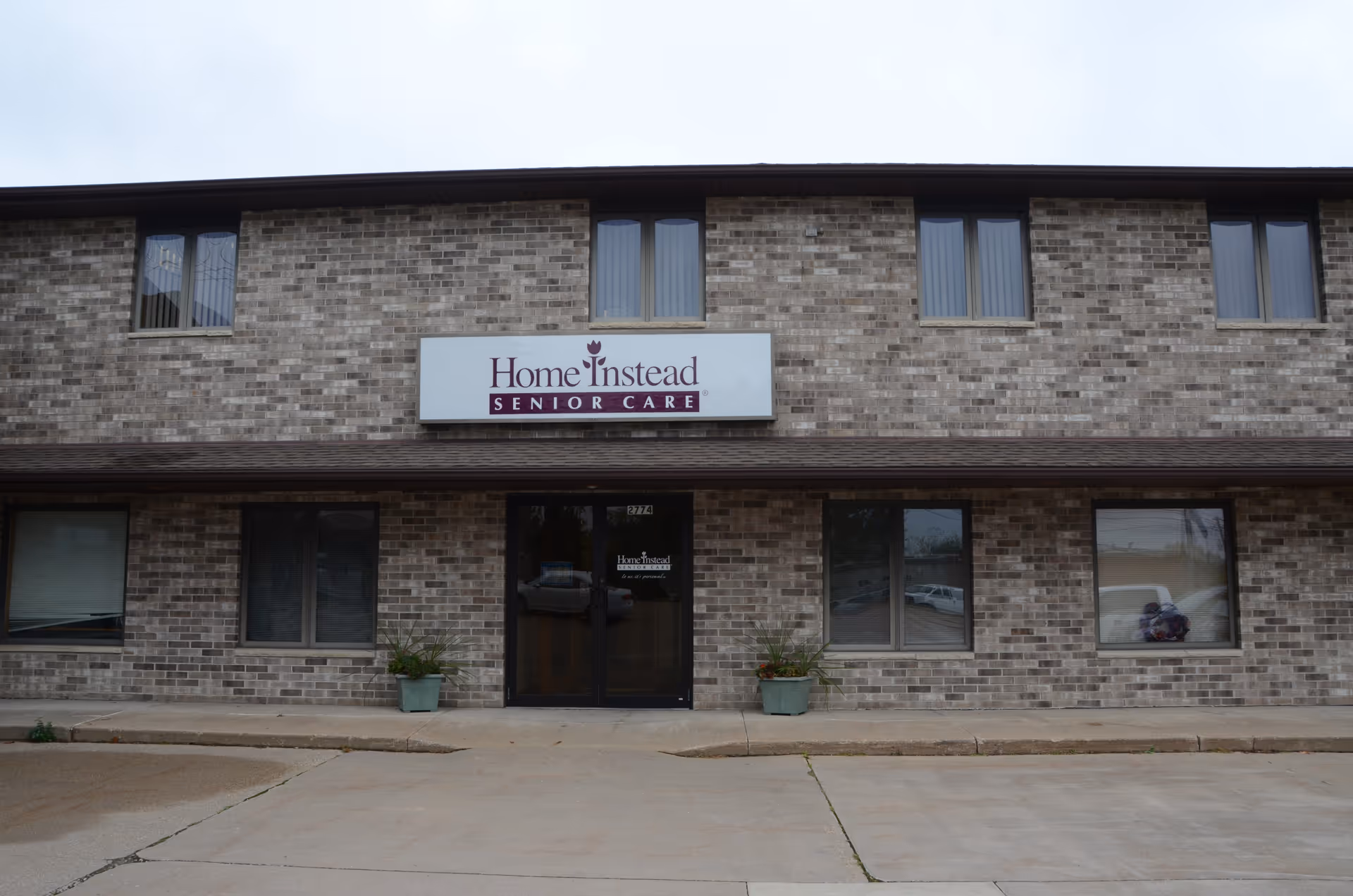 Brick two-story building with Home Instead Senior Care sign and entrance doors.