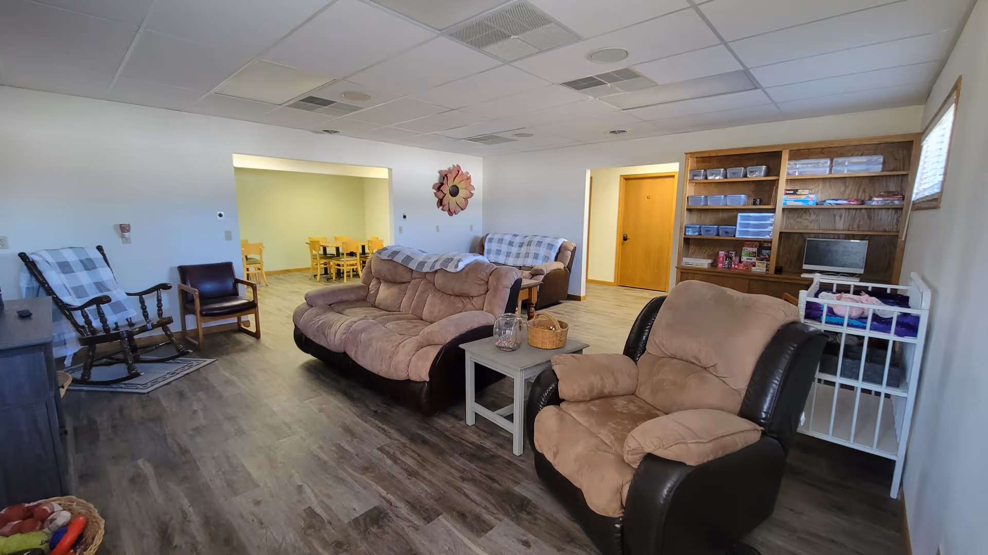 Spacious living room with multiple seating, a small crib, and a built-in bookshelf.