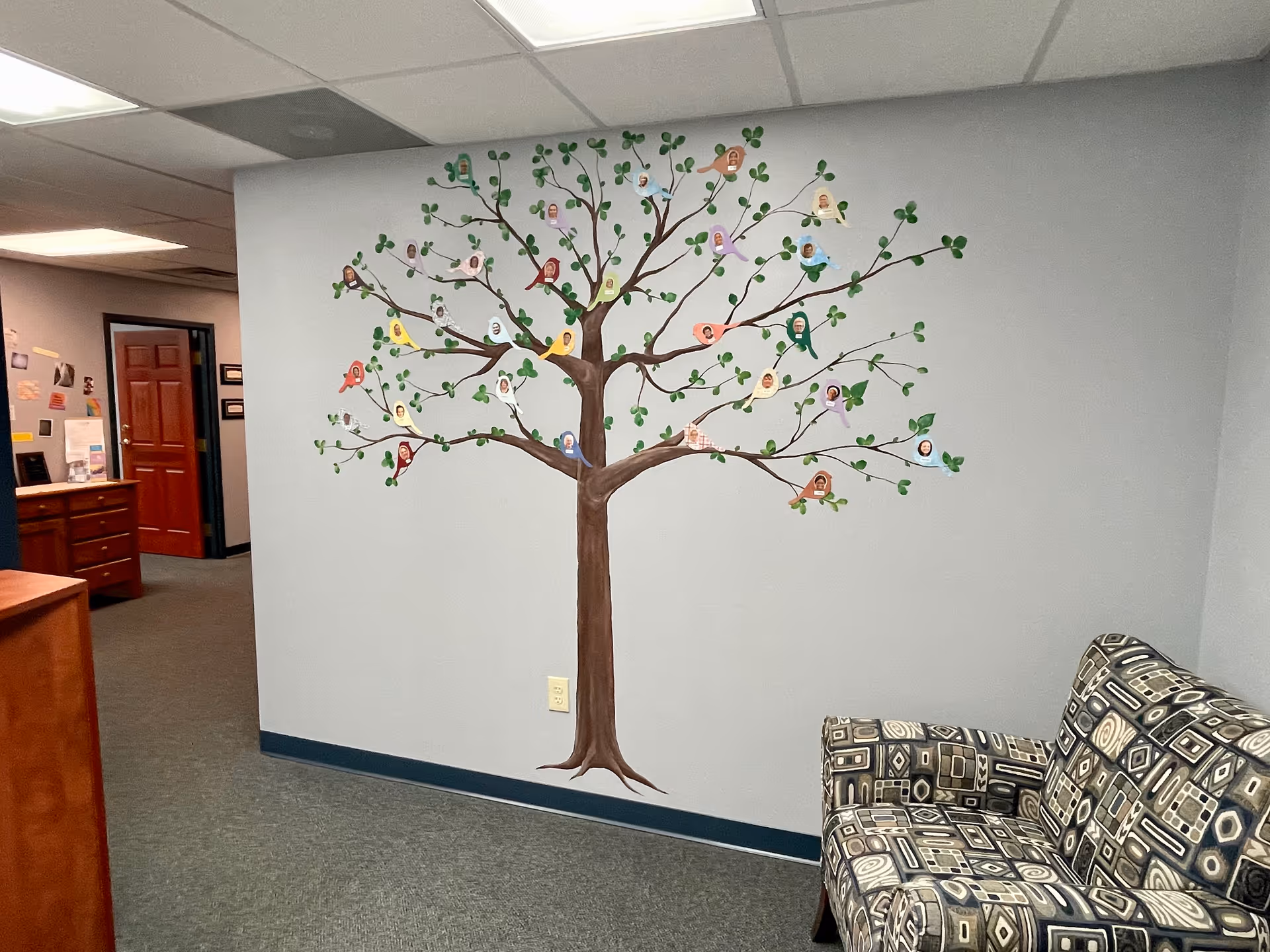 Interior hallway with a large tree mural on the wall and a patterned sofa.