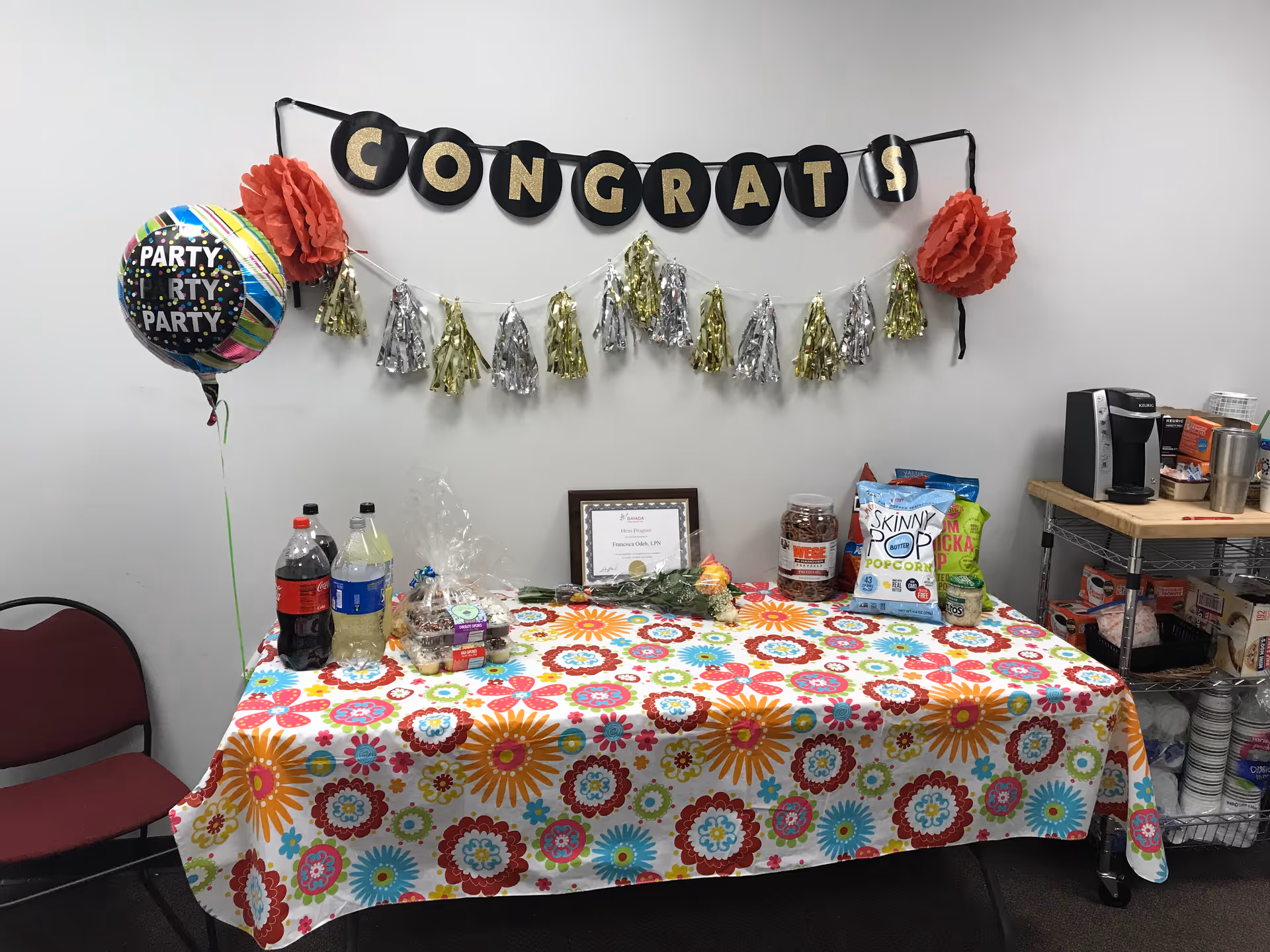 A colorful party table with snacks, drinks, and a 'CONGRATS' banner.