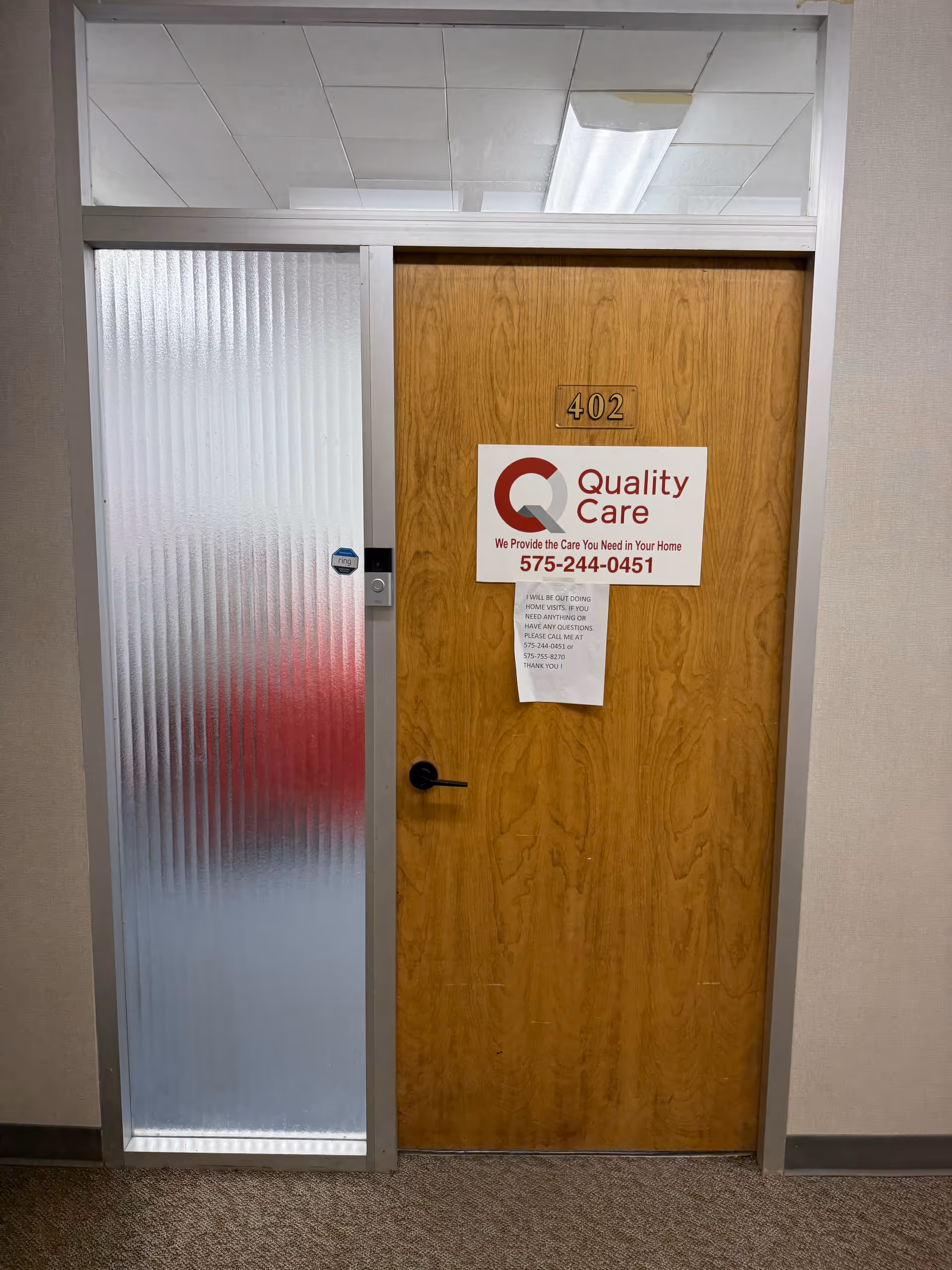 Wooden door with the number 402 and a Quality Care sign in a hallway.
