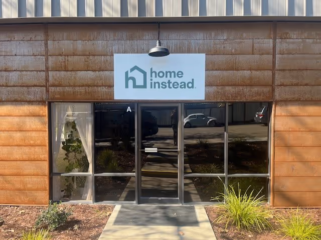 Front entrance of a facility with a Home Instead sign and glass doors.