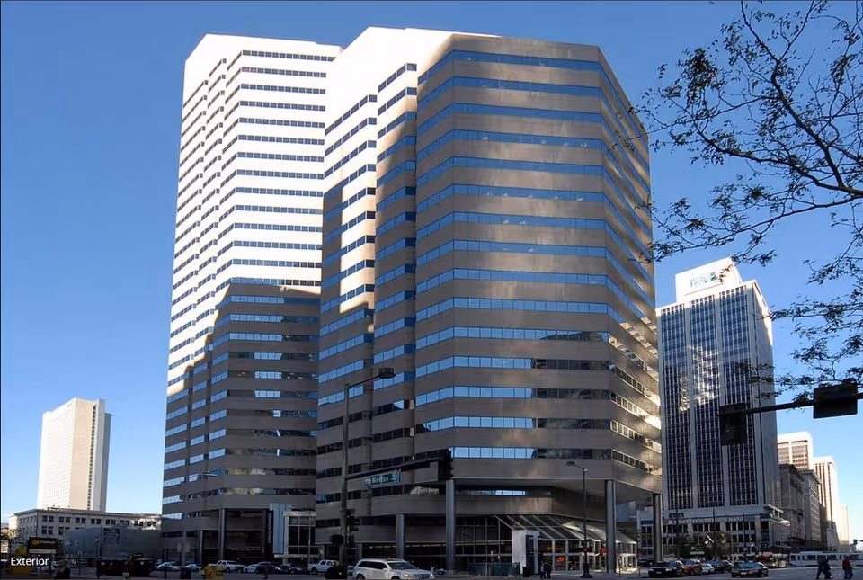 Tall glass-clad office towers rise along a busy city street in daylight.