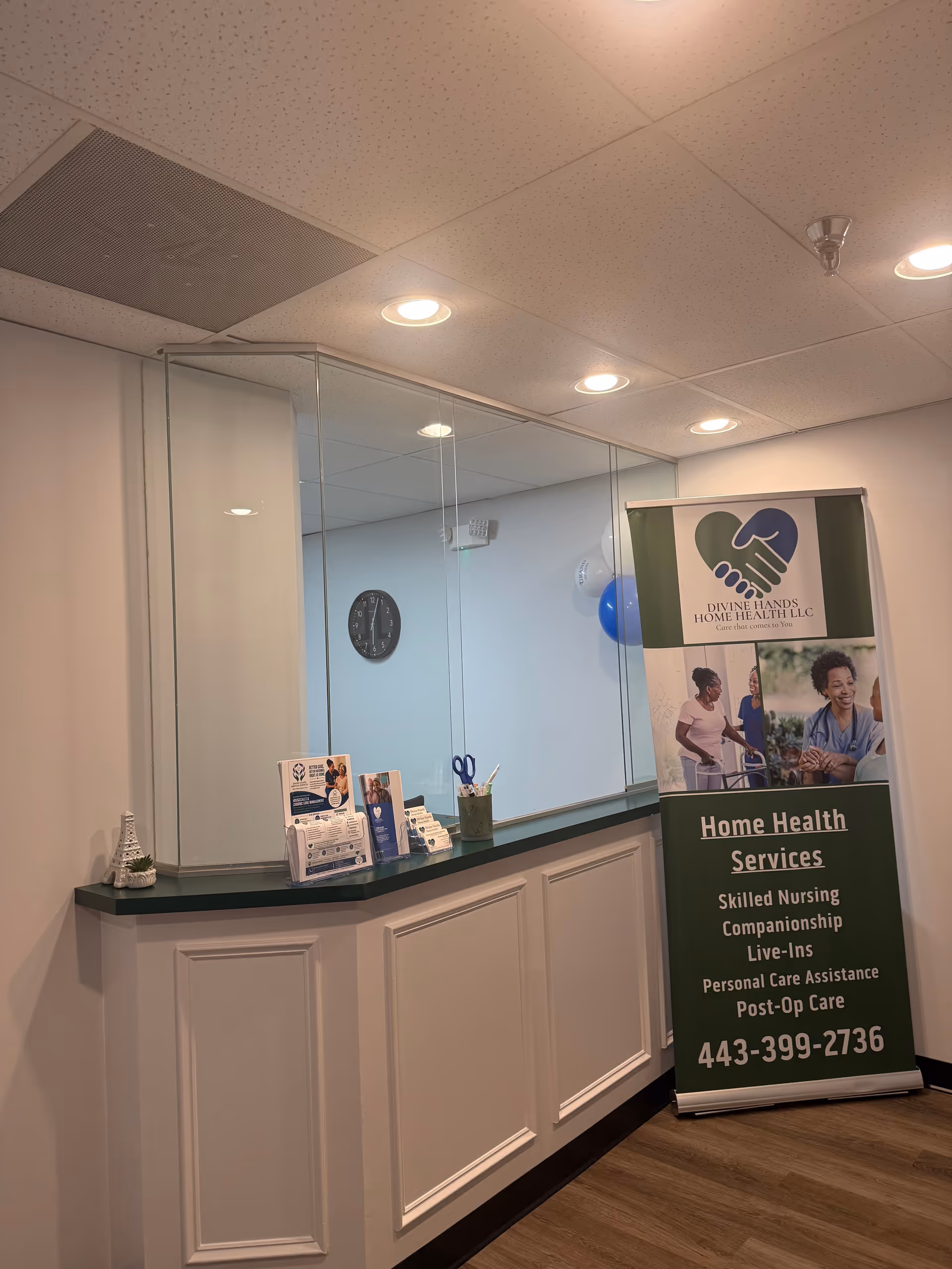 Reception counter with brochure stand and banner for Divine Hands Home Health LLC in interior.