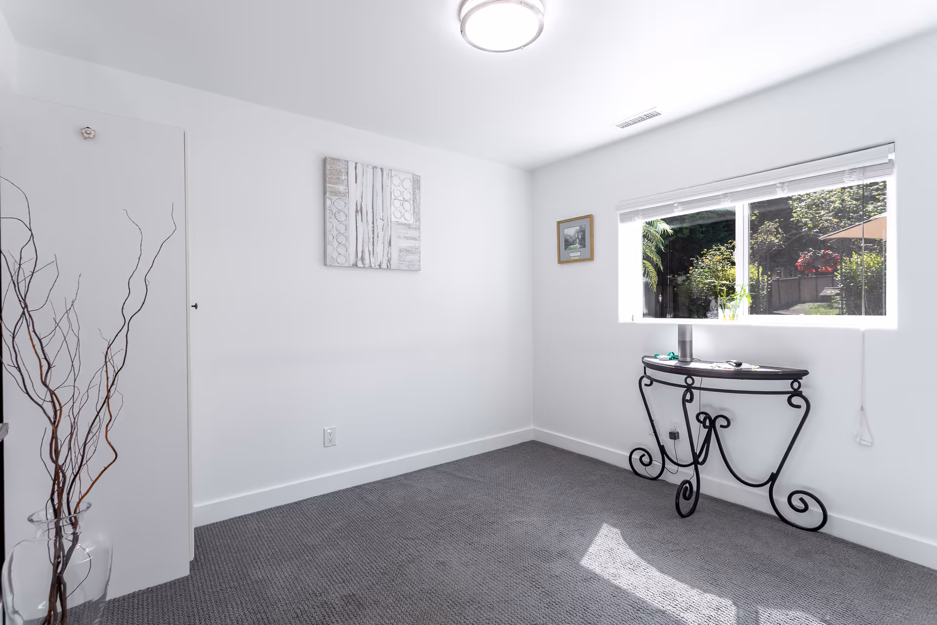 Bright, white-walled room with a window and a decorative curved-iron console table.