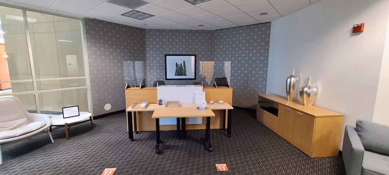 Reception area with a curved desk, seating, and a sideboard in a modern lobby.