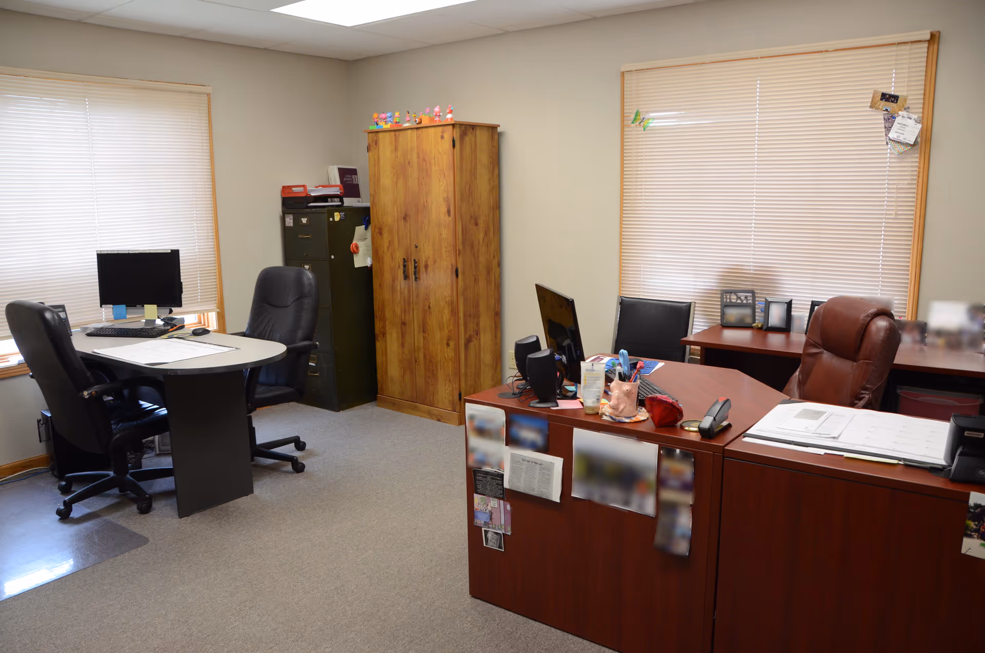 Interior office area with desks, chairs, computer, filing cabinet, and wooden storage cabinet.