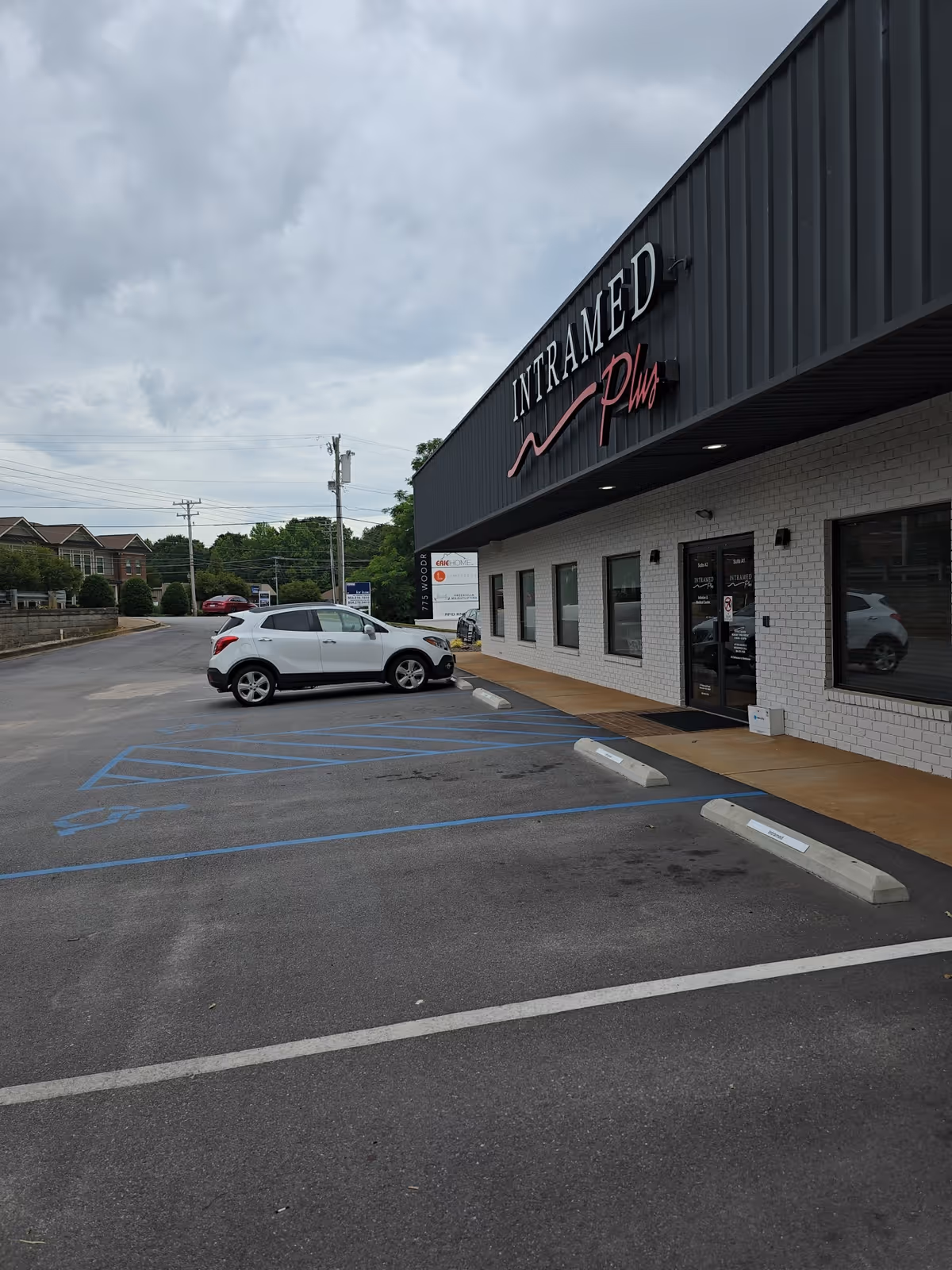 Exterior view of Intramed Plus facility with parking lot and accessible entrance.