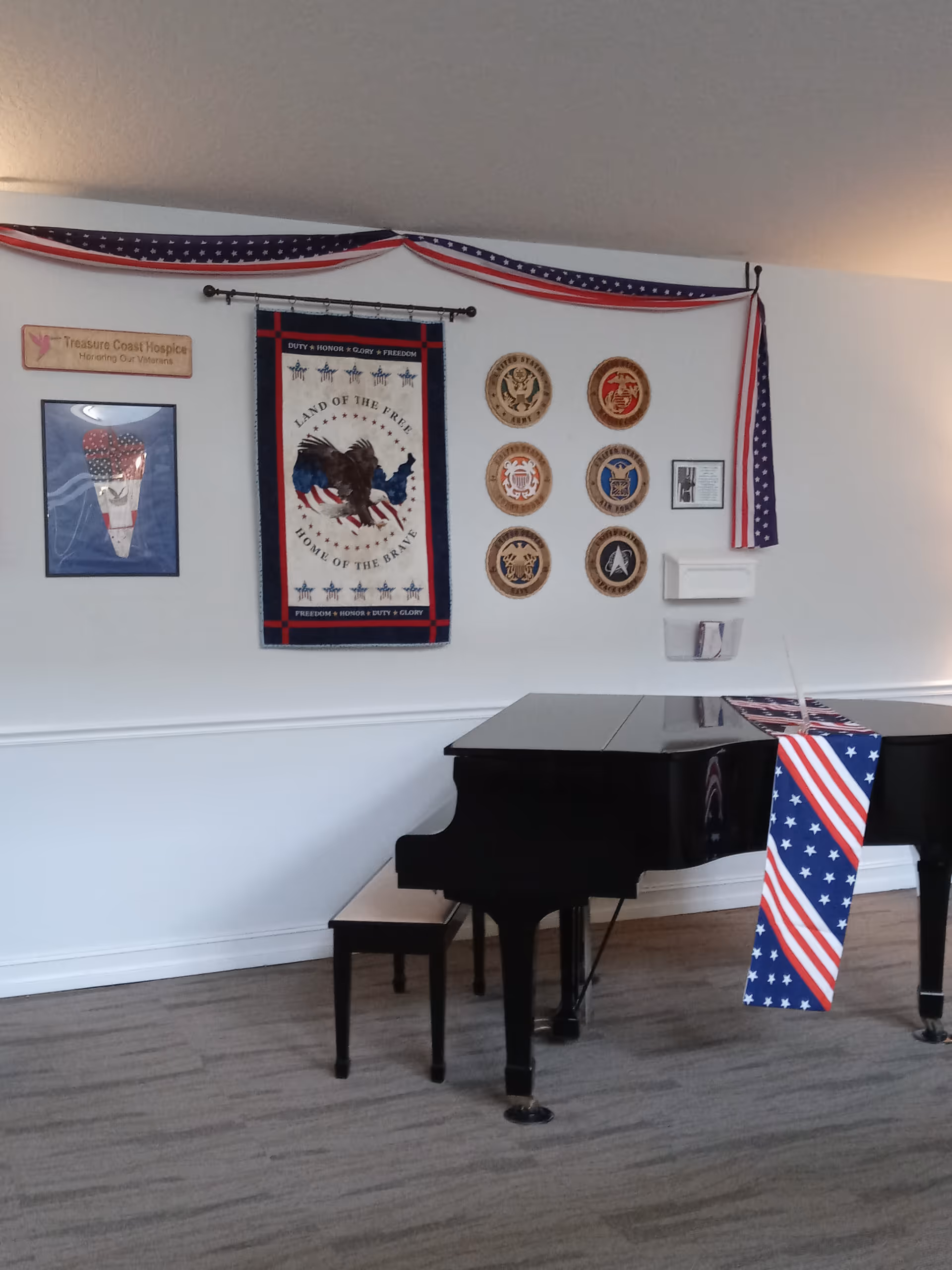 Black grand piano in a decorated room with patriotic banners and plaques.