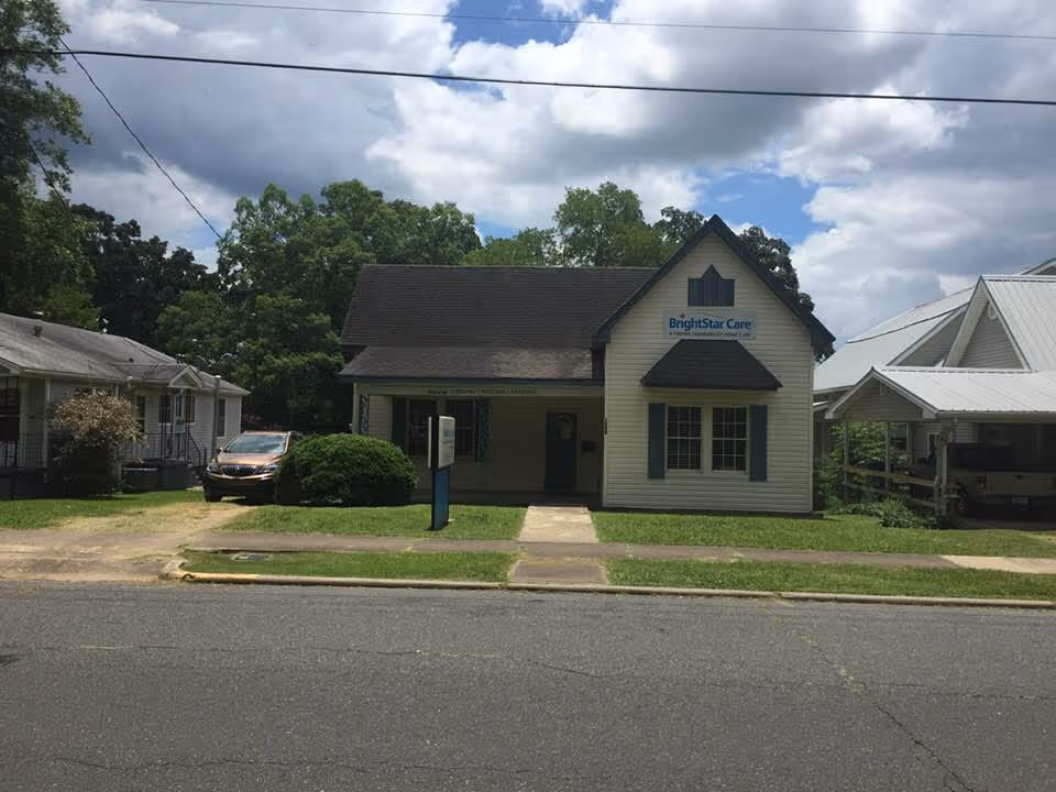 Small white building with BrightStar Care sign, front lawn, and sidewalk along the street.