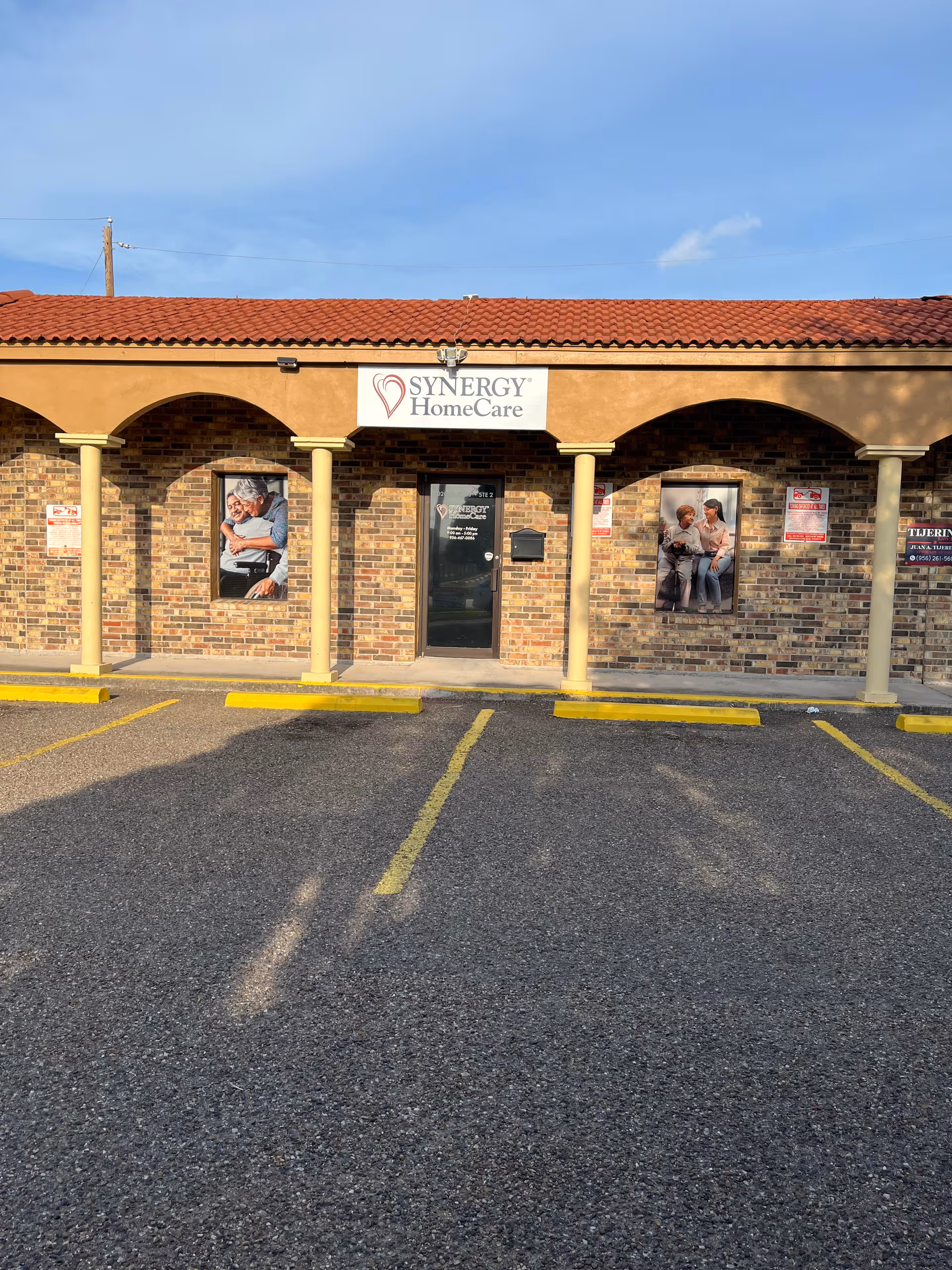 Exterior view of a Synergy HomeCare storefront with brick arches and a parking lot.