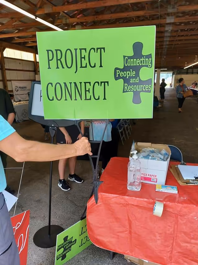 Bright green PROJECT CONNECT sign at an indoor booth in a large hall.