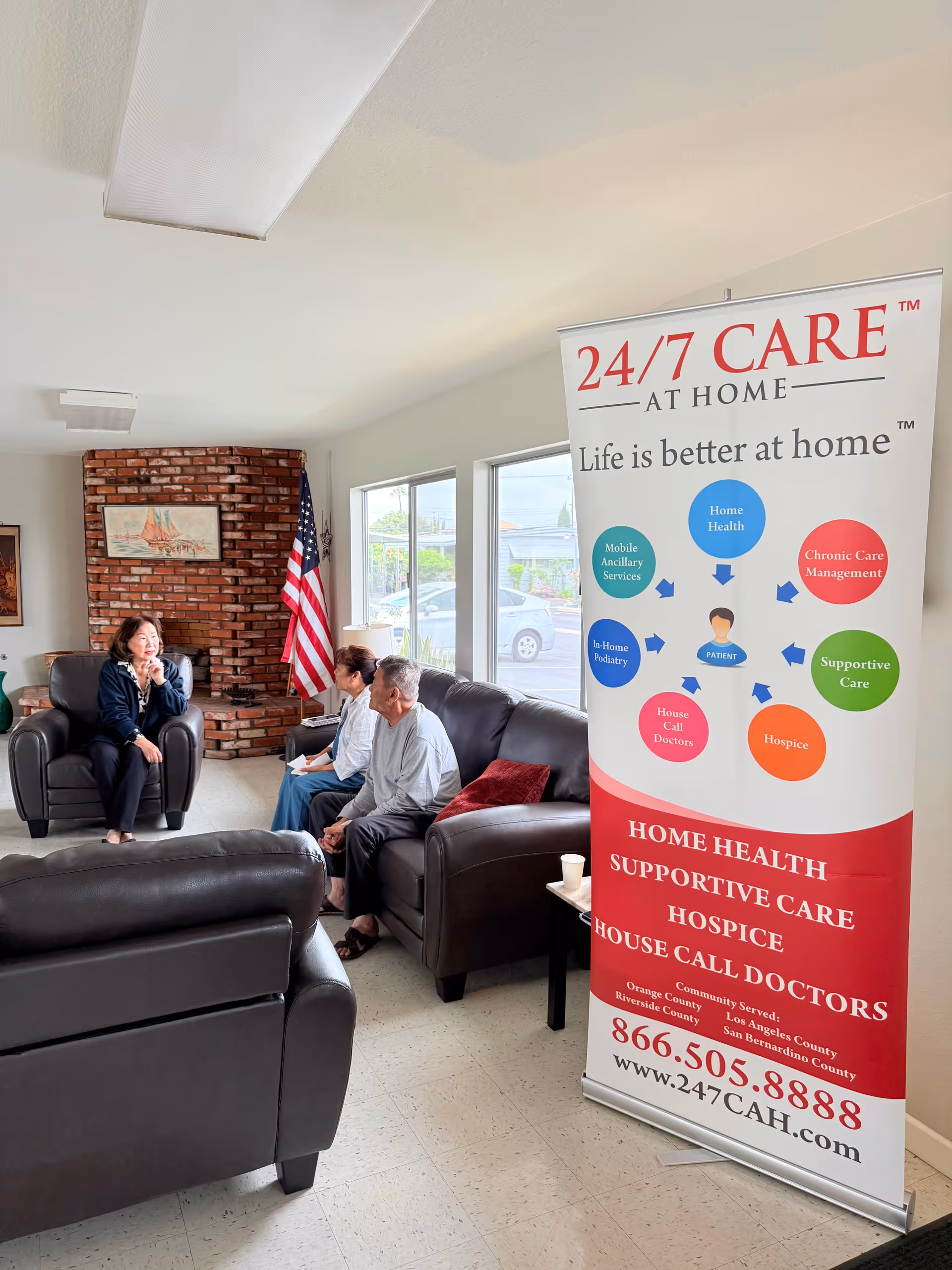 Residents sit in a lounge area as a banner promotes 24/7 Care At Home.