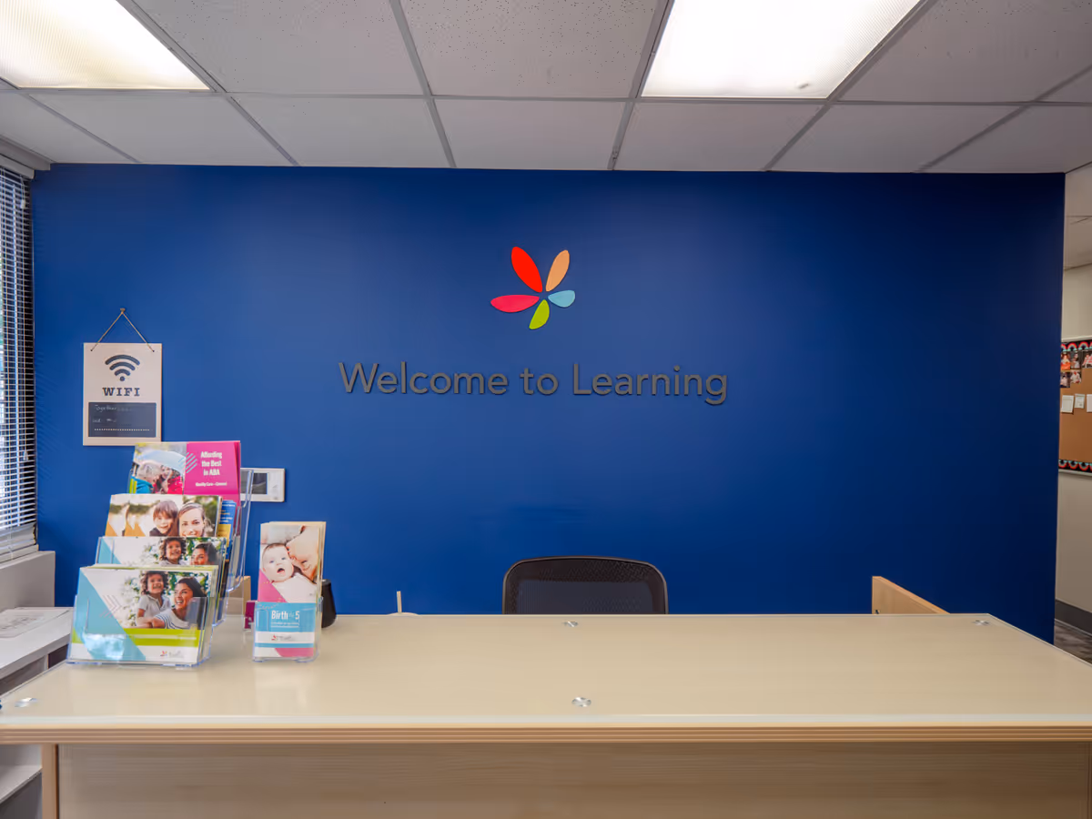 Reception desk in a bright blue wall space with Welcome to Learning sign and brochures.