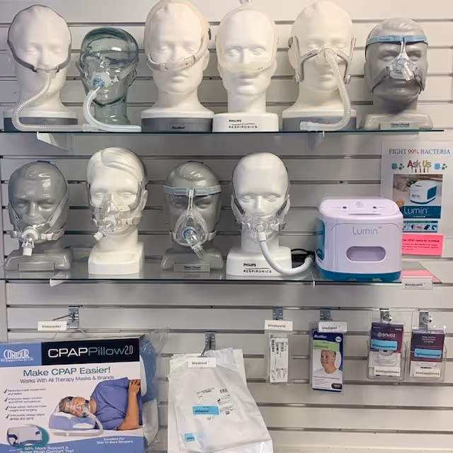 Display of CPAP masks and a Lumin device on shelves in a medical supply store.