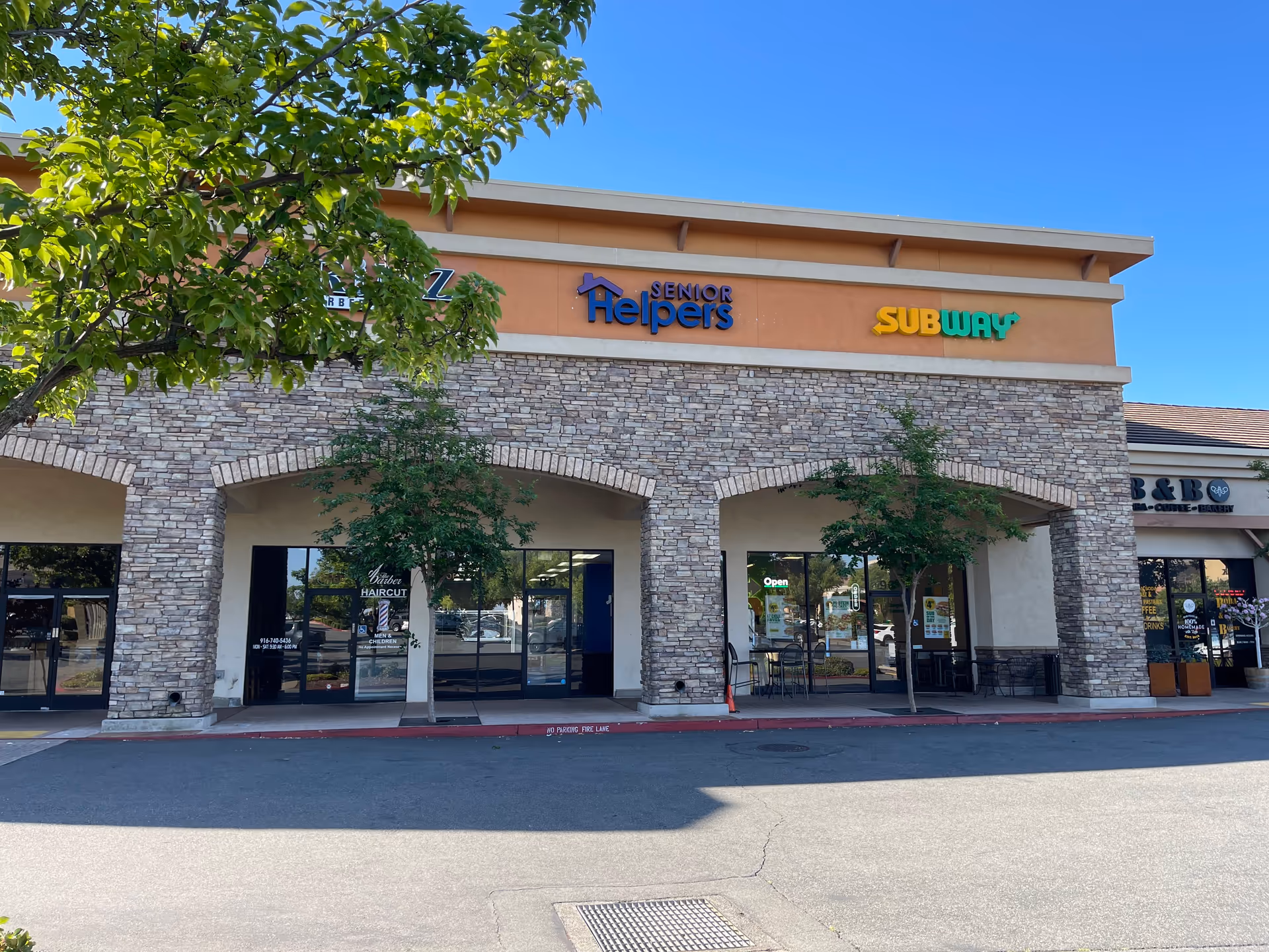 Commercial strip mall storefronts featuring Senior Helpers and Subway signage under a stone façade.