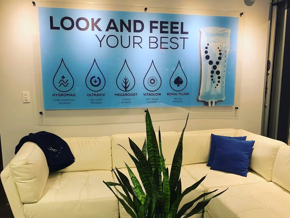 White sectional sofa in a lobby with a blue IV therapy poster.