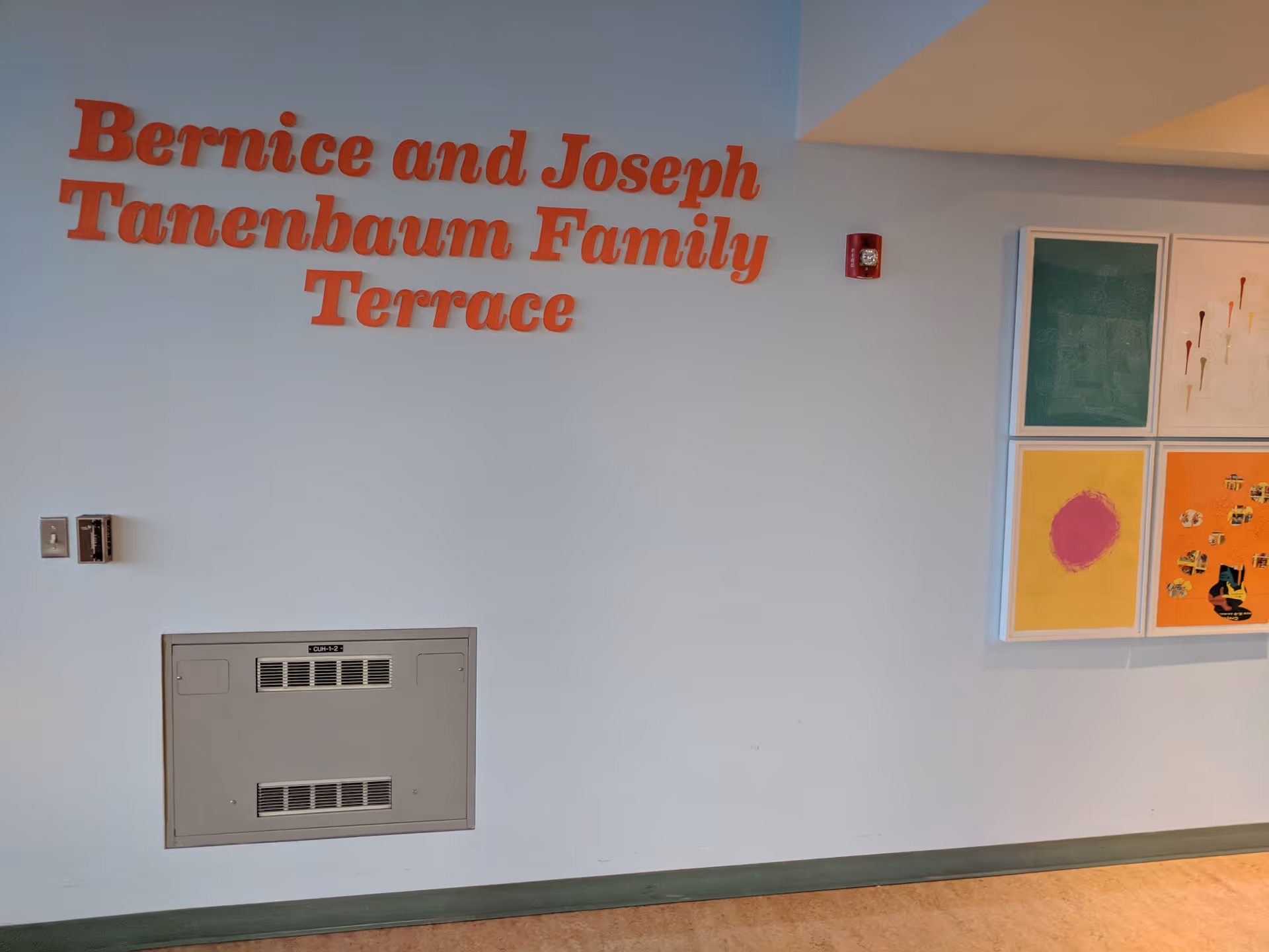 A pale blue hallway wall with a red sign reading Bernice and Joseph Tanenbaum Family Terrace.