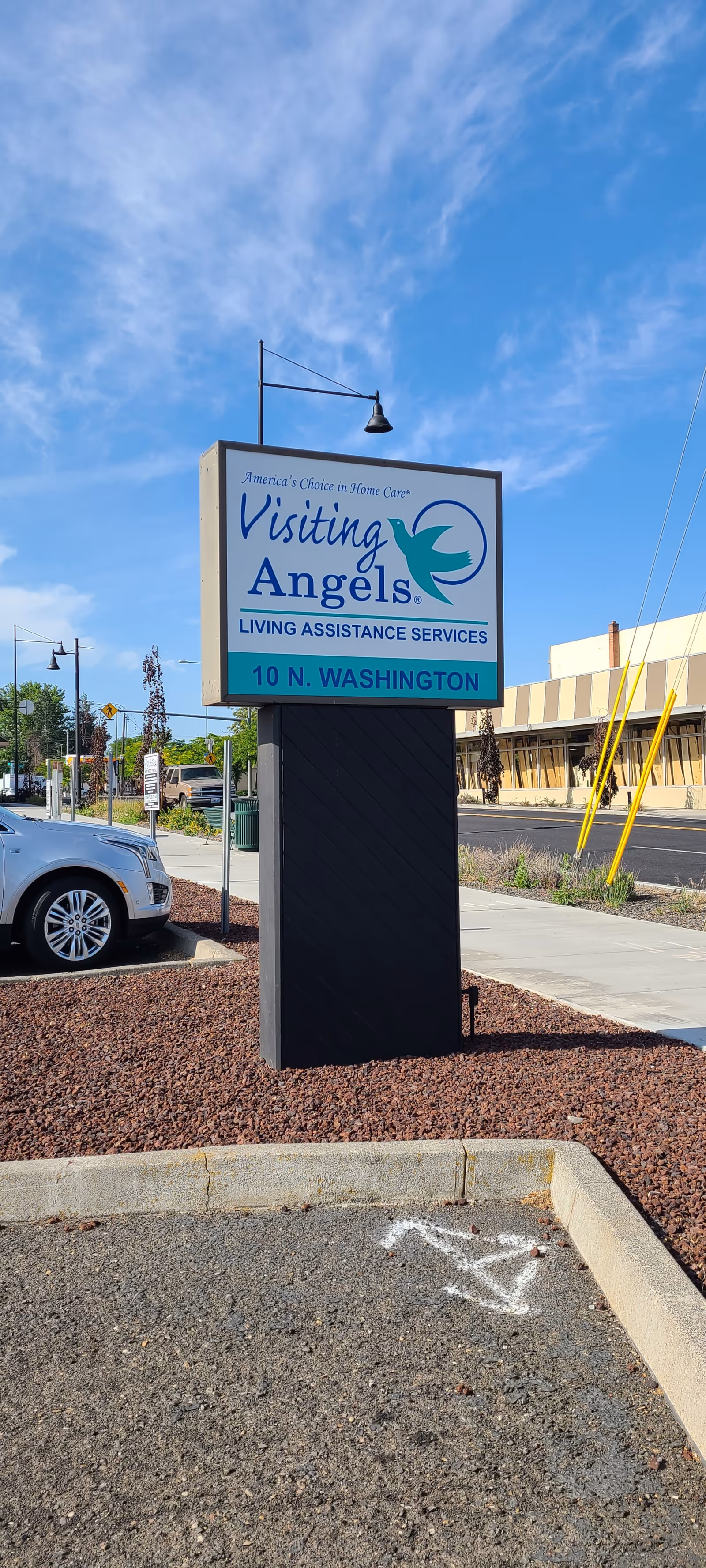 Outdoor sign for Visiting Angels Senior Home Care in parking lot with building in background.