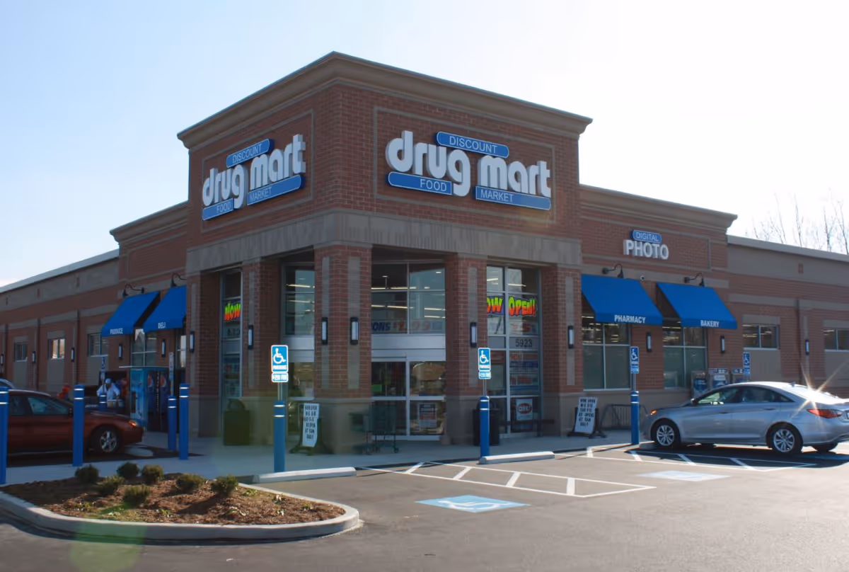A brick Discount Drug Mart storefront with blue awnings and a parking lot.