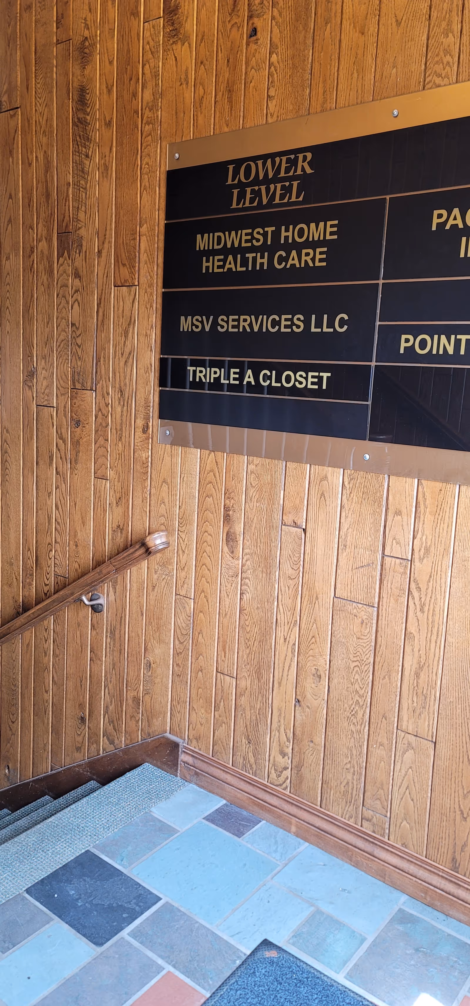 Wood-paneled interior hallway with a large sign listing Midwest Home Health Care beside stairs.