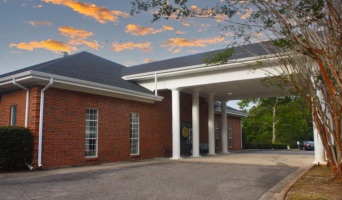 Brick nursing facility exterior with a covered entrance and white columns.